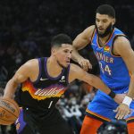 Phoenix Suns guard Devin Booker (1) shields the ball from Oklahoma City Thunder forward Kenrich Williams during the second half of an NBA basketball game, Thursday, Dec. 23, 2021, in Phoenix. The Suns won 113-101. (AP Photo/Rick Scuteri)