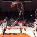 Arizona center Christian Koloko (35) dunks between Illinois center Kofi Cockburn, left, and guard Da'Monte Williams during the first half of an NCAA college basketball game Saturday, Dec. 11, 2021, in Champaign, Ill. (AP Photo/Charles Rex Arbogast)