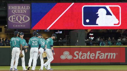 Seattle Mariners gather as the MLB logo is shown during a review of an attempted catch by right fie...