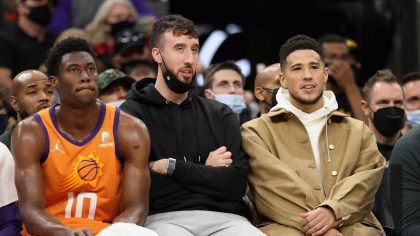 Jalen Smith #10, Frank Kaminsky #8 and Devin Booker #1 of the Phoenix Suns watch from the bench dur...