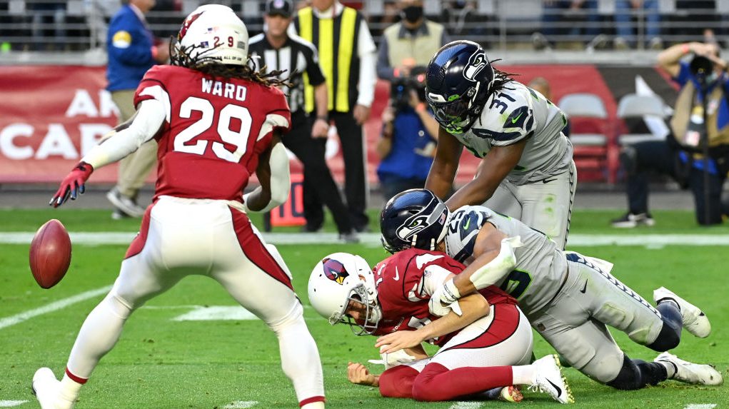 Travis Homer #25 of the Seattle Seahawks forces a fumble by Andy Lee #14 of the Arizona Cardinals a...