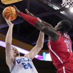 UCLA guard Jaime Jaquez Jr., left, shoots as Arizona center Oumar Ballo defends during the second half of an NCAA college basketball game Tuesday, Jan. 25, 2022, in Los Angeles. (AP Photo/Mark J. Terrill)