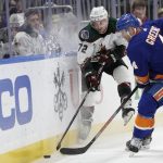 Arizona Coyotes center Travis Boyd (72) and New York Islanders defenseman Andy Greene (4) fight for a puck during the first period of an NHL hockey game, Friday, Jan. 21, 2022, in Elmont, N.Y. (AP Photo/Corey Sipkin).