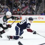 Colorado Avalanche center Nathan MacKinnon (29) dives for the puck against Arizona Coyotes left wing Antoine Roussel (26) during the first period of an NHL hockey game Friday, Jan. 14, 2022, in Denver. (AP Photo/Jack Dempsey)