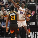 Utah Jazz's Mike Conley, rear, and Hassan Whiteside (21) defend as Phoenix Suns center Bismack Biyombo (18) shoots in the first half during an NBA basketball game Wednesday, Jan. 26, 2022, in Salt Lake City. (AP Photo/Rick Bowmer)