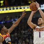 Phoenix Suns guard Devin Booker (1) shoots as Utah Jazz's Danuel House Jr., left, defends in the second half during an NBA basketball game Wednesday, Jan. 26, 2022, in Salt Lake City. (AP Photo/Rick Bowmer)