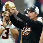 Oklahoma State head coach Mike Gundy hoists the Fiesta Bowl Champions Trophy after the Fiesta Bowl NCAA college football game against Notre Dame, Saturday, Jan. 1, 2022, in Glendale, Ariz. Oklahoma State won 37-35. (AP Photo/Ross D. Franklin)