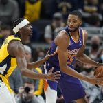 Phoenix Suns' Mikal Bridges (25) is defended by Indiana Pacers' Justin Holiday, left, during the first half of an NBA basketball game, Friday, Jan. 14, 2022, in Indianapolis. (AP Photo/Darron Cummings)