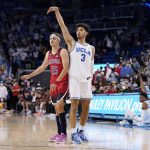 UCLA guard Johnny Juzang (3) holds the pose as he shoots a three-point shot as Arizona guard Kerr Kriisa watches during the second half of an NCAA college basketball game Tuesday, Jan. 25, 2022, in Los Angeles. (AP Photo/Mark J. Terrill)