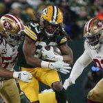 Green Bay Packers' Aaron Jones tries to get away from San Francisco 49ers' Fred Warner (54) and D.J. Jones during the first half of an NFC divisional playoff NFL football game Saturday, Jan. 22, 2022, in Green Bay, Wis. (AP Photo/Morry Gash)