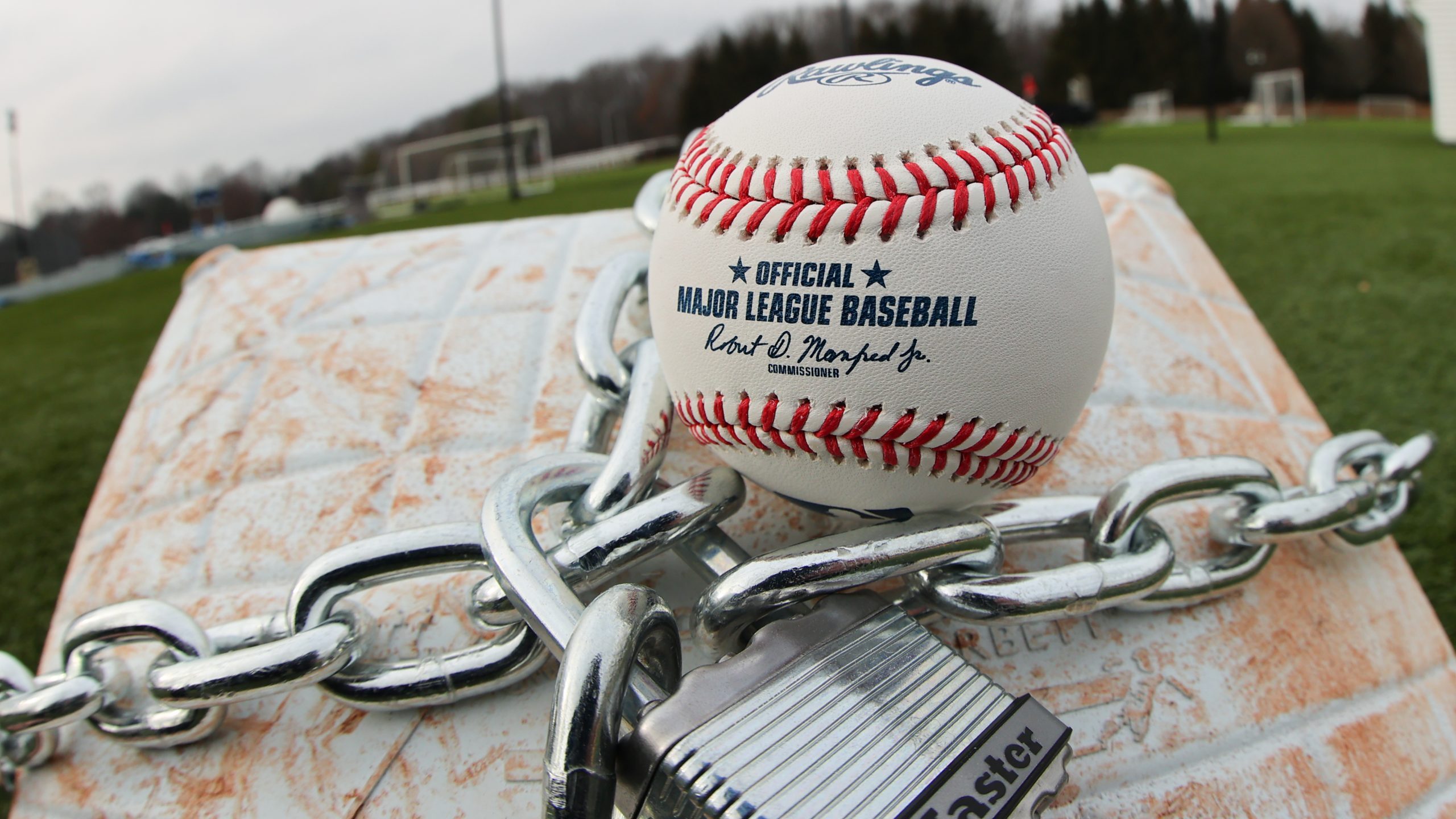 An official MLB baseball sits on top of an MLB game-used base with a lock and chain around it to re...