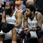 Brooklyn Nets guard James Harden, left, and guard Kyrie Irving watch from the bench during the second half of an NBA basketball game against the Phoenix Suns, Tuesday, Feb. 1, 2022, in Phoenix. The Suns defeated the Nets 121-111. (AP Photo/Matt York)