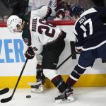 Arizona Coyotes left wing Antoine Roussel, left, fights to clear the puck from Colorado Avalanche center Tyson Jost during the first period of an NHL hockey game Tuesday, Feb. 1, 2022, in Denver. (AP Photo/David Zalubowski)