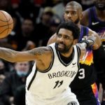 Brooklyn Nets guard Kyrie Irving (11) reaches for the loose ball against the Phoenix Suns during the second half of an NBA basketball game, Tuesday, Feb. 1, 2022, in Phoenix. (AP Photo/Matt York)