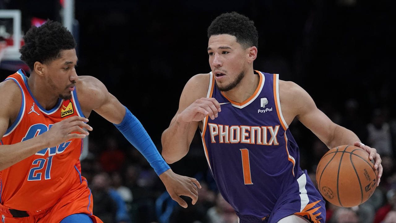 Phoenix Suns guard Devin Booker (1) drives around Oklahoma City Thunder guard Aaron Wiggins (21) in...