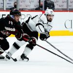 Arizona Coyotes defenseman Shayne Gostisbehere (14) and Los Angeles Kings center Phillip Danault (24) reach for the puck during the second period of an NHL hockey game Wednesday, Feb. 23, 2022, in Glendale, Ariz. (AP Photo/Ross D. Franklin)