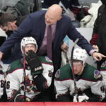 Arizona Coyotes head coach Andre Tourigny talks to players before overtime in the team's NHL hockey game against the Colorado Avalanche Tuesday, Feb. 1, 2022, in Denver. Arizona won 3-2 in a shootout. (AP Photo/David Zalubowski)