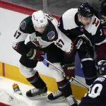 Arizona Coyotes left wing Lawson Crouse, left, fights for control of the puck with Colorado Avalanche defensemen Jack Johnson and Samuel Girard, right, during the first period of an NHL hockey game Tuesday, Feb. 1, 2022, in Denver. (AP Photo/David Zalubowski)