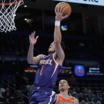Phoenix Suns guard Devin Booker (1) shoots in front of tpot7=, right, in the second half of an NBA basketball game Thursday, Feb. 24, 2022, in Oklahoma City. (AP Photo/Sue Ogrocki)