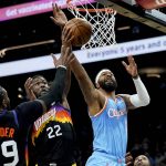 Los Angeles Clippers forward Marcus Morris Sr. shoots as Phoenix Suns center Deandre Ayton (22) defends during the second half of an NBA basketball game Tuesday, Feb. 15, 2022, in Phoenix. The Suns won 103-96. (AP Photo/Matt York)