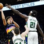 Phoenix Suns forward Cameron Johnson, left, shoots over Milwaukee Bucks guards Jrue Holiday (21) and Pat Connaughton during the first half of an NBA basketball game Thursday, Feb. 10, 2022, in Phoenix. (AP Photo/Ross D. Franklin)