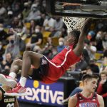 Arizona guard Bennedict Mathurin hangs from the rim after dunking against Colorado in the first half of an NCAA college basketball game Saturday, Feb. 26 2022, in Boulder, Colo. (AP Photo/David Zalubowski)