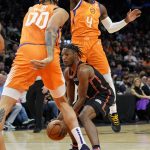 New York Knicks guard Immanuel Quickley looks to pass as Phoenix Suns guard Aaron Holiday (4) and center JaVale McGee (00) defend during the first half of an NBA basketball game, Friday, March 4, 2022, in Phoenix. (AP Photo/Matt York)