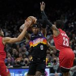 Phoenix Suns forward Torrey Craig (0) drive s as Portland Trail Blazers forward Trendon Watford (2) and guard Ben McLemore (23) defend during the second half of an NBA basketball game, Wednesday, March 2, 2022, in Phoenix. (AP Photo/Matt York)