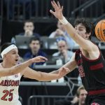 Arizona's Kerr Kriisa (25) passes around Stanford's Maxime Raynaud (42) during the first half of an NCAA college basketball game in the quarterfinal round of the Pac-12 tournament Thursday, March 10, 2022, in Las Vegas. (AP Photo/John Locher)