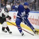 Toronto Maple Leafs center Auston Matthews (34) and Arizona Coyotes defenseman J.J. Moser (62) battle for the puck along the boards during second-period NHL hockey game action in Toronto, Ontario, Thursday, March 10, 2022. (Frank Gunn/The Canadian Press via AP)