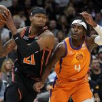New York Knicks forward Cam Reddish (21) drives as Phoenix Suns guard Aaron Holiday (4) defends during the first half of an NBA basketball game, Friday, March 4, 2022, in Phoenix. (AP Photo/Matt York)