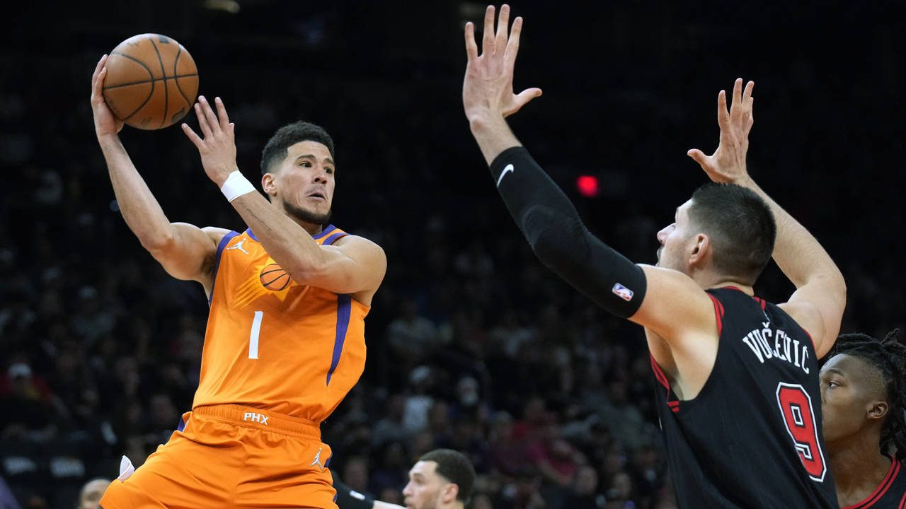Phoenix Suns guard Devin Booker (1) looks to pass around Chicago Bulls center Nikola Vucevic during...