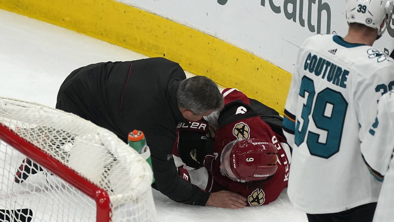 A trainer attends to Arizona Coyotes' Clayton Keller (9), who collided against the boards during th...