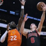 Chicago Bulls guard Alex Caruso (6) drives on Phoenix Suns center Deandre Ayton during the first half of an NBA basketball game Friday, March 18, 2022, in Phoenix. (AP Photo/Rick Scuteri)