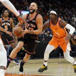 New York Knicks guard Evan Fournier (13) drives as Phoenix Suns guard Aaron Holiday (4) defends during the first half of an NBA basketball game, Friday, March 4, 2022, in Phoenix. (AP Photo/Matt York)