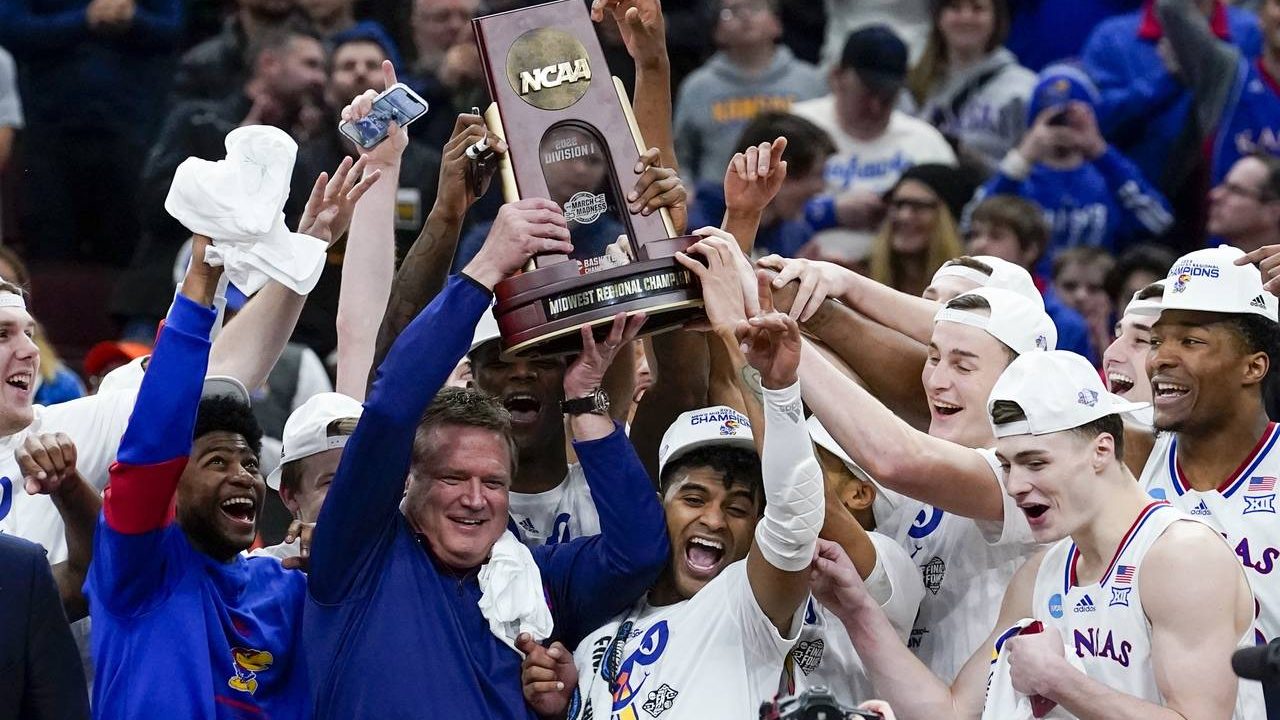 Kansas head coach Bill Self and players hold up the winning trophy after a college basketball game ...