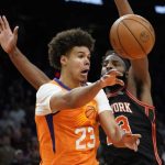 Phoenix Suns forward Cameron Johnson (23) dishes off as New York Knicks center Mitchell Robinson (23) defends during the second half of an NBA basketball game, Friday, March 4, 2022, in Phoenix. The Phoenix Suns defeated the Knicks 115-114. (AP Photo/Matt York)