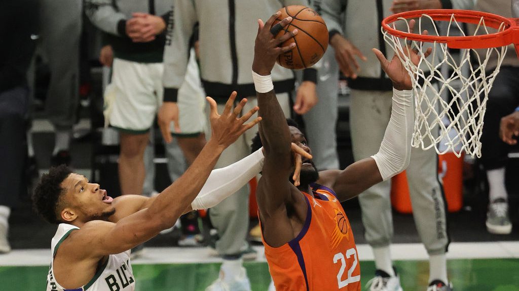 Deandre Ayton #22 of the Phoenix Suns grabs a rebound against Giannis Antetokounmpo #34 of the Milw...