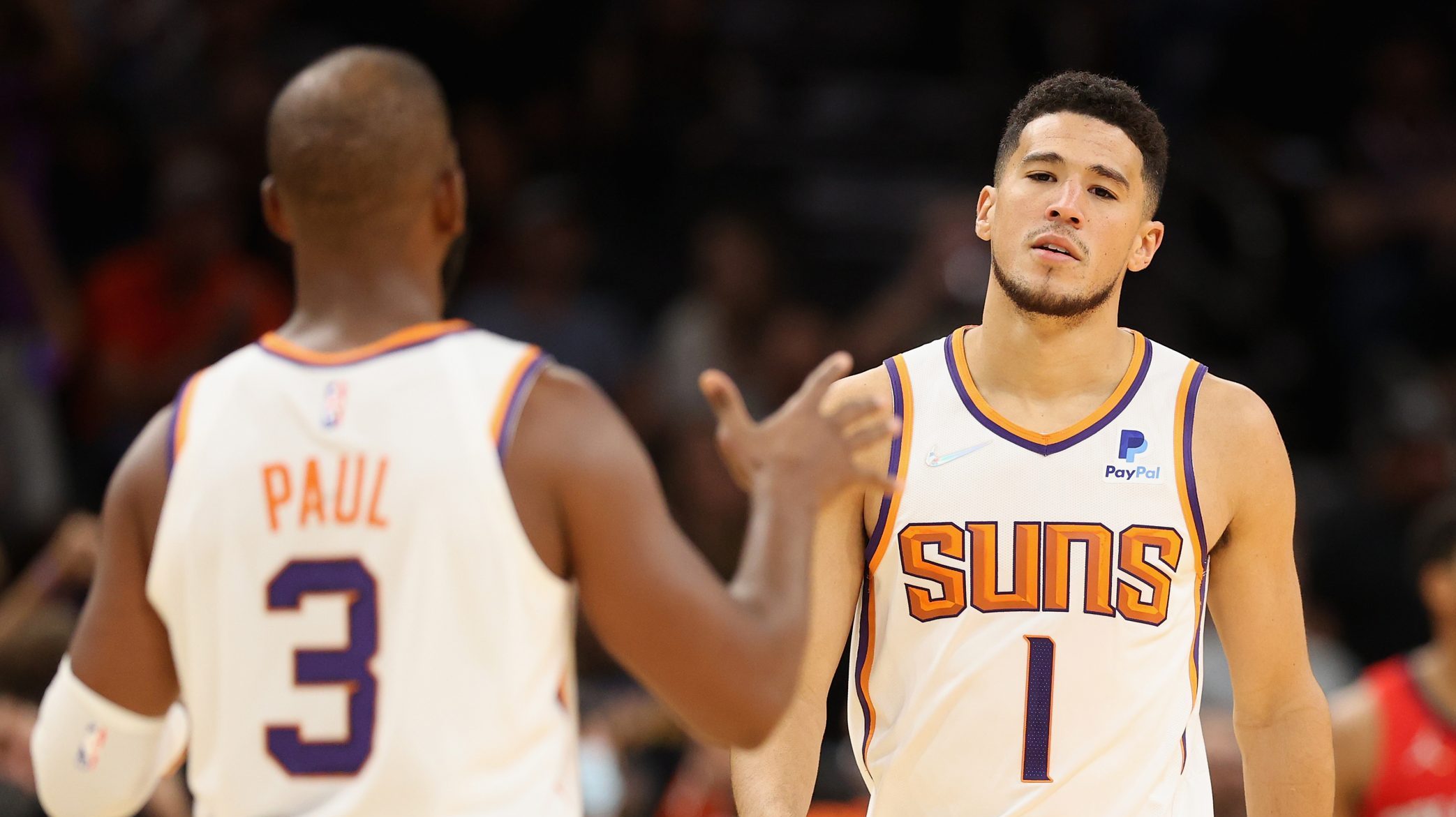 Devin Booker #1 of the Phoenix Suns reacts to Chris Paul #3 after Booker hit a three-point shot aga...