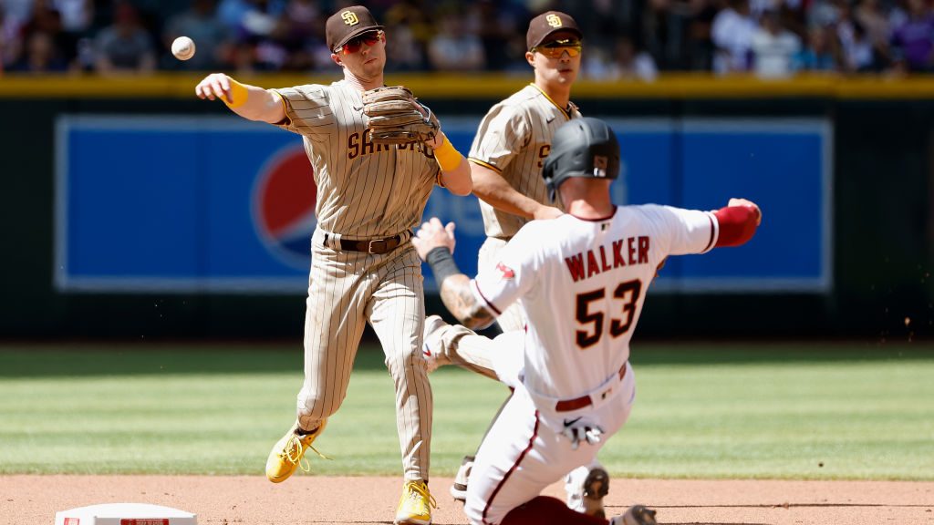Infielder Jake Cronenworth #9 of the San Diego Padres throws over the sliding Christian Walker #53 ...