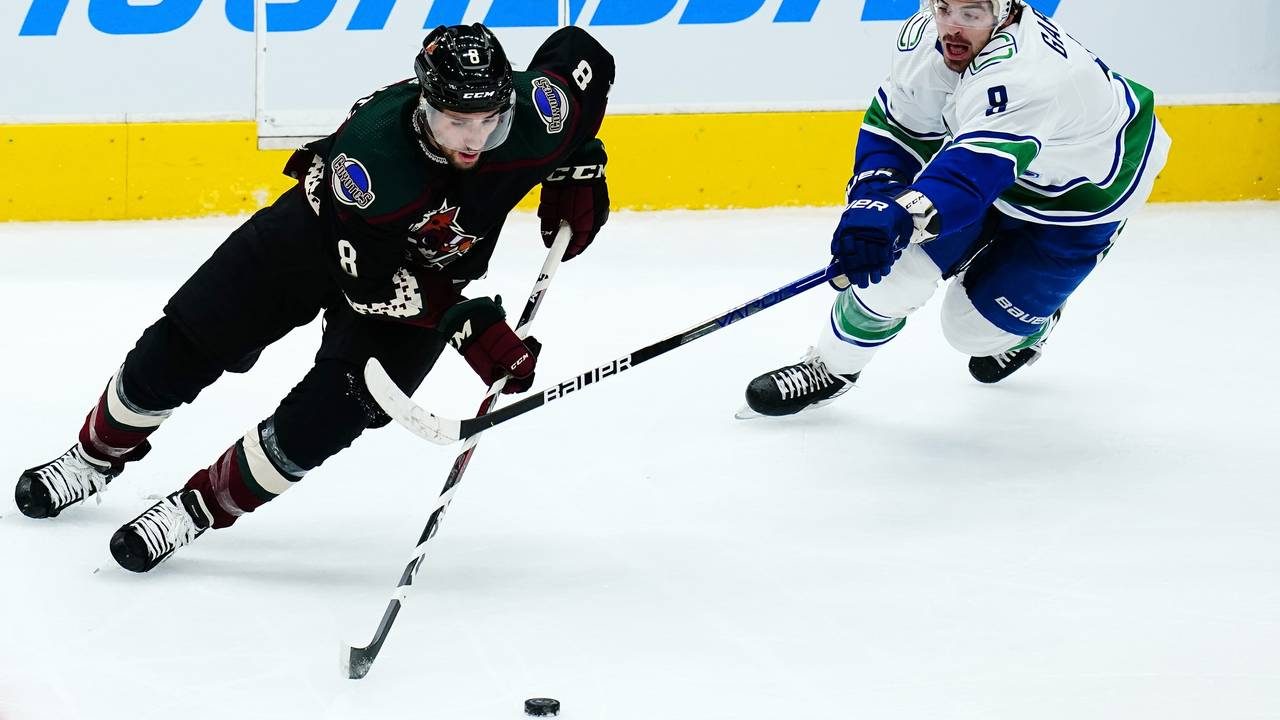 Arizona Coyotes center Nick Schmaltz, left, skates with the puck against Vancouver Canucks right wi...