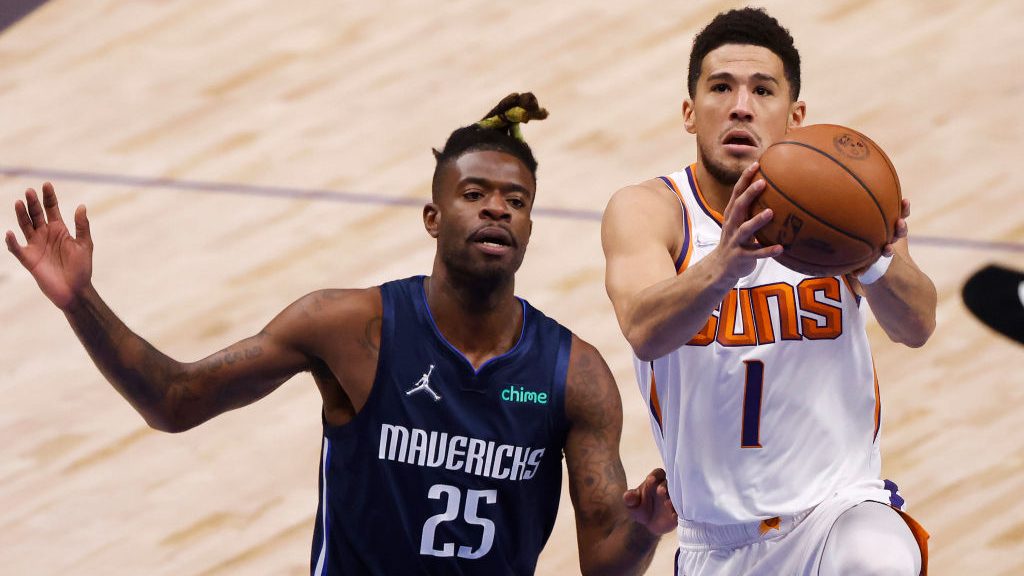 Devin Booker #1 of the Phoenix Suns drives to the basket against Reggie Bullock #25 of the Dallas M...