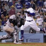 Los Angeles Dodgers' Mookie Betts, right, scores on a double by Freddie Freeman as Arizona Diamondbacks catcher Jose Herrera takes a late throw during the eighth inning of a baseball game Tuesday, May 17, 2022, in Los Angeles. (AP Photo/Mark J. Terrill)