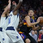 Phoenix Suns guard Devin Booker (1) is pressured by Dallas Mavericks forward Dorian Finney-Smith (10) and Dallas Mavericks center Dwight Powell, left, during the second half of Game 2 of an NBA basketball second-round playoff series, Wednesday, May 4, 2022, in Phoenix. (AP Photo/Matt York)