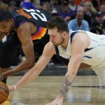 Dallas Mavericks guard Luka Doncic, right, and Phoenix Suns forward Mikal Bridges (25) scramble for a loose ball during the second half of Game 2 of an NBA basketball second-round playoff series, Wednesday, May 4, 2022, in Phoenix. (AP Photo/Matt York)