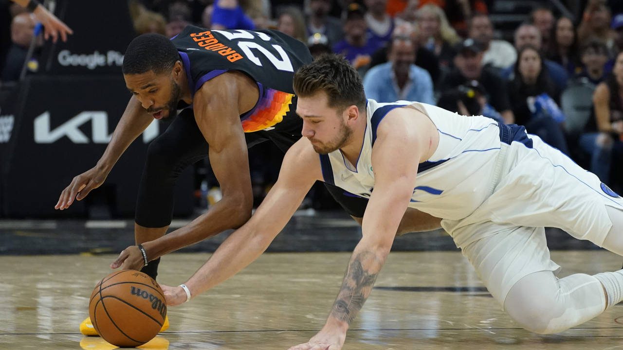 Dallas Mavericks guard Luka Doncic, right, and Phoenix Suns forward Mikal Bridges (25) scramble for...