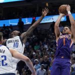 Phoenix Suns guard Devin Booker (1) shoots past Dallas Mavericks forward Dorian Finney-Smith (10) and forward Maxi Kleber (42) during the first half of Game 3 of an NBA basketball second-round playoff series, Friday, May 6, 2022, in Dallas. (AP Photo/Tony Gutierrez)