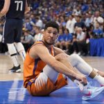 
              Phoenix Suns guard Devin Booker (1) looks up at an official standing nearby after being knocked to the floor while shooting with no foul call made in the first half of Game 4 of an NBA basketball second-round playoff series against the Dallas Mavericks, Sunday, May 8, 2022, in Dallas. (AP Photo/Tony Gutierrez)
            