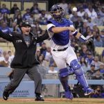 Los Angeles Dodgers catcher Austin Barnes, right, attempts to throw out Arizona Diamondbacks' Alek Thomas at first as home plate umpire David Rackley calls a foul ball during the second inning of a baseball game Tuesday, May 17, 2022, in Los Angeles. (AP Photo/Mark J. Terrill)