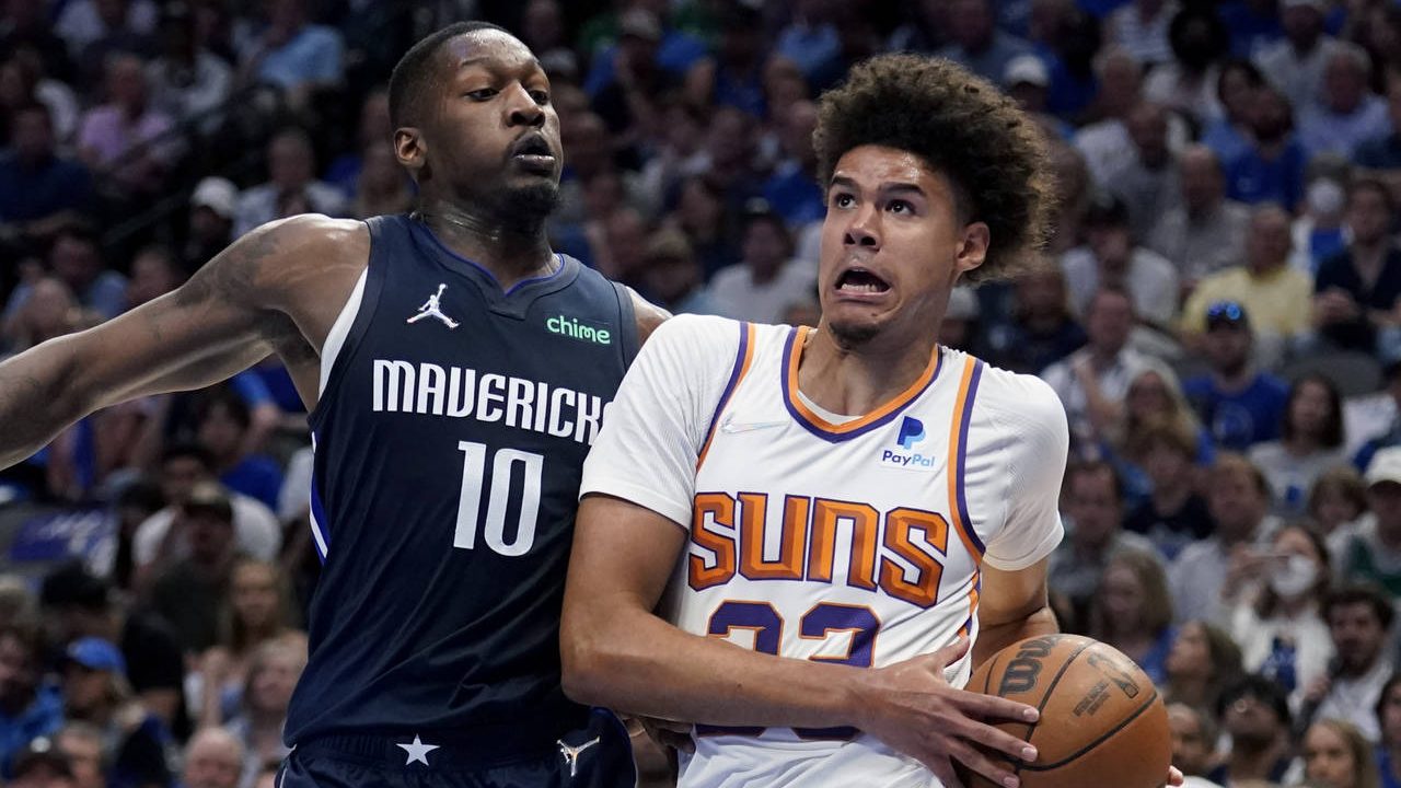 Phoenix Suns forward Cameron Johnson, right, drives to the basket against Dallas Mavericks forward ...